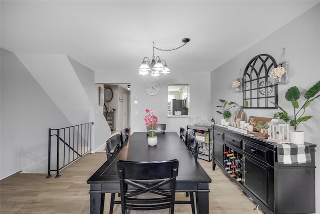 dining space with light wood-style flooring, baseboards, and a chandelier