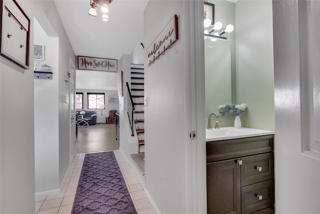 interior space featuring a sink, stairway, baseboards, and light tile patterned floors