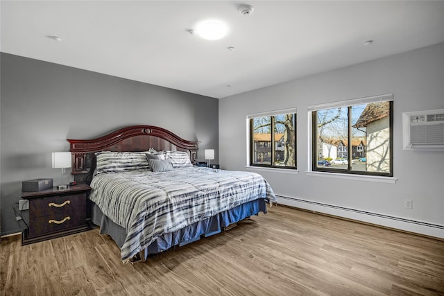 bedroom featuring a baseboard radiator, an AC wall unit, and wood finished floors