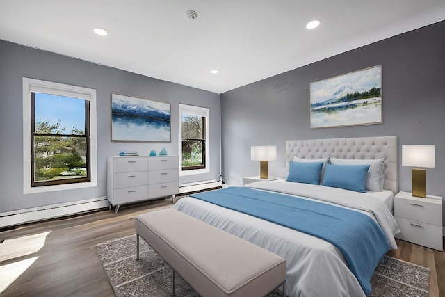 bedroom featuring recessed lighting, a baseboard heating unit, and wood finished floors