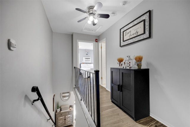 corridor featuring light wood-style flooring, an upstairs landing, and baseboards