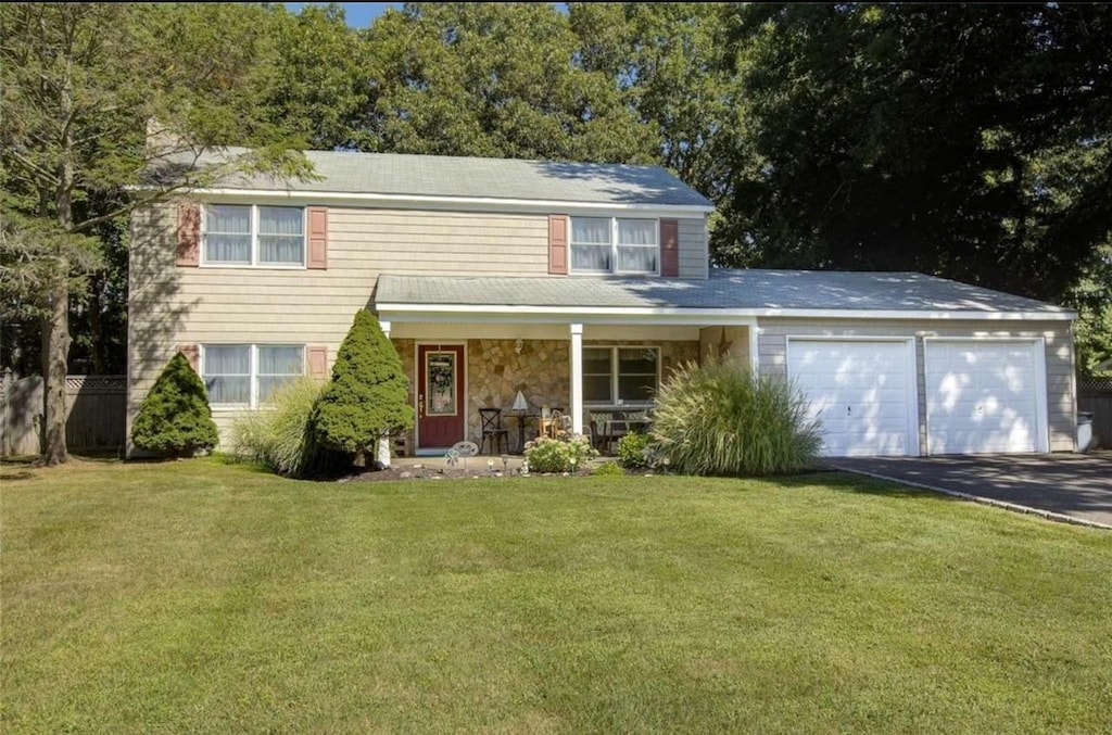 view of front of house with a front lawn, driveway, covered porch, and an attached garage