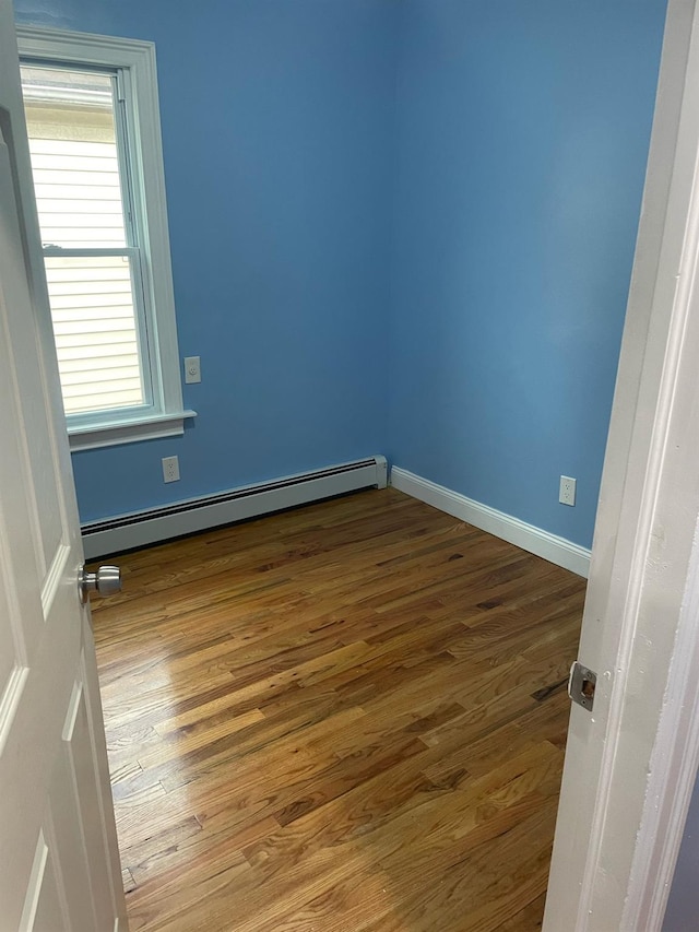 114-27 135th St, South Ozone Park, NY 11420 - unfurnished bedroom featuring baseboard heating, baseboards, and wood finished floors