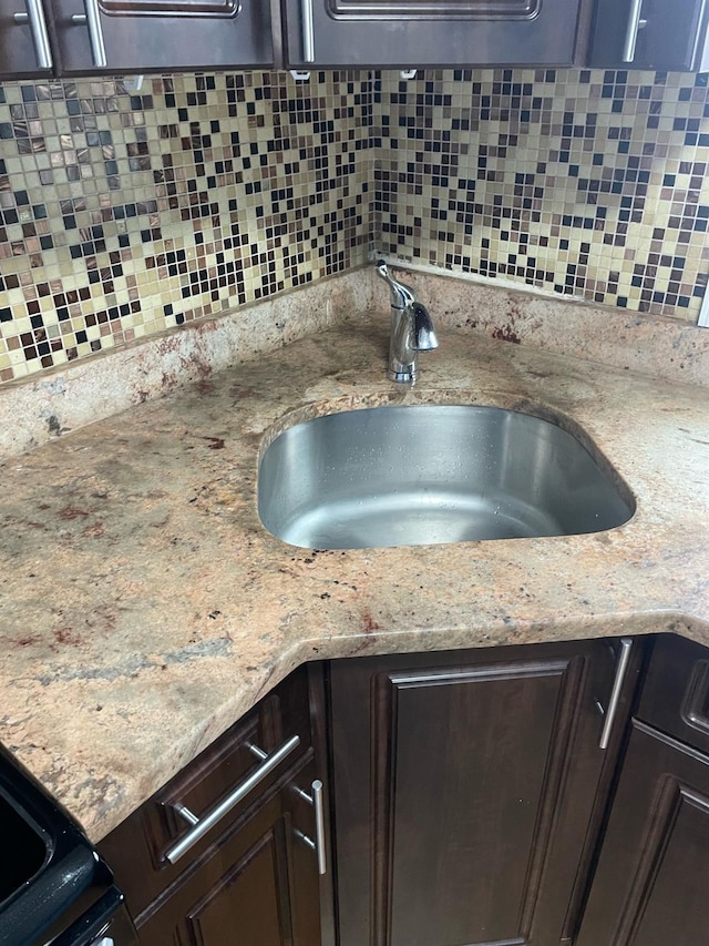 114-27 135th St, South Ozone Park, NY 11420 - room details with decorative backsplash, dark brown cabinets, light stone countertops, and a sink