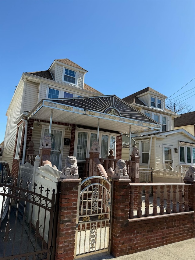 view of front facade featuring a fenced front yard, a shingled roof, and a gate