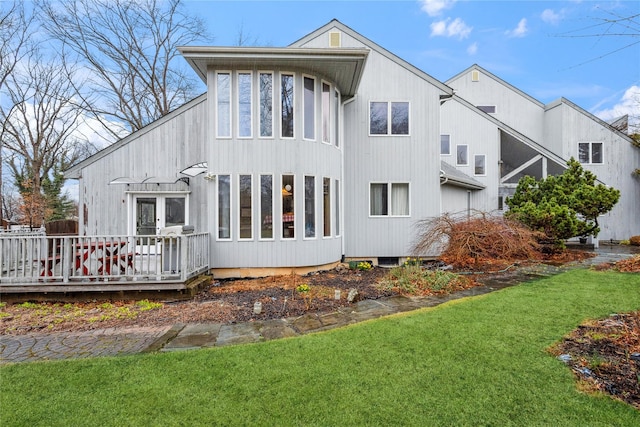 rear view of house featuring a wooden deck and a lawn