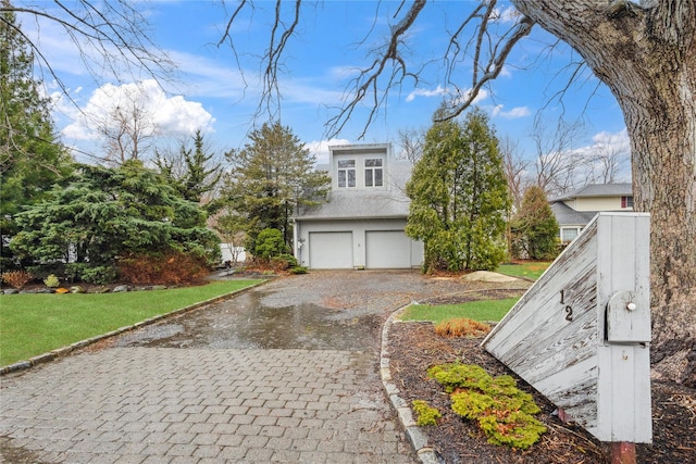 view of side of home with an attached garage, decorative driveway, and a yard