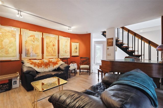 living room with light wood-style flooring, rail lighting, and stairway