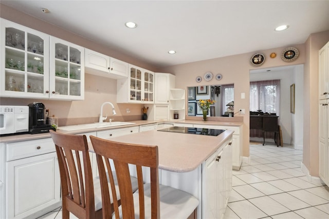 kitchen with a sink, white appliances, light tile patterned floors, light countertops, and a kitchen bar