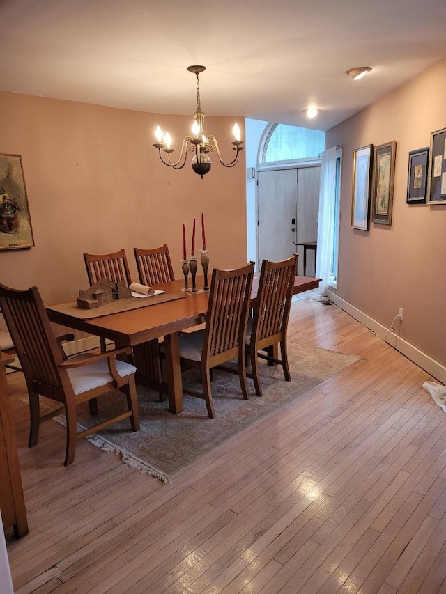 dining space with baseboards, a chandelier, and light wood-style floors
