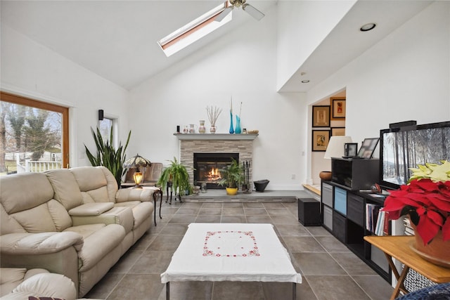tiled living area with a skylight, a fireplace, high vaulted ceiling, and a ceiling fan
