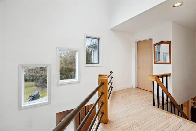 hall featuring recessed lighting, plenty of natural light, light wood-type flooring, and an upstairs landing