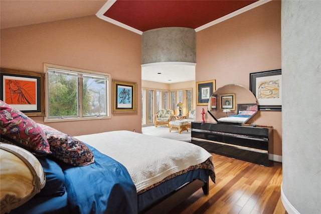 bedroom featuring wood finished floors, high vaulted ceiling, and ornamental molding
