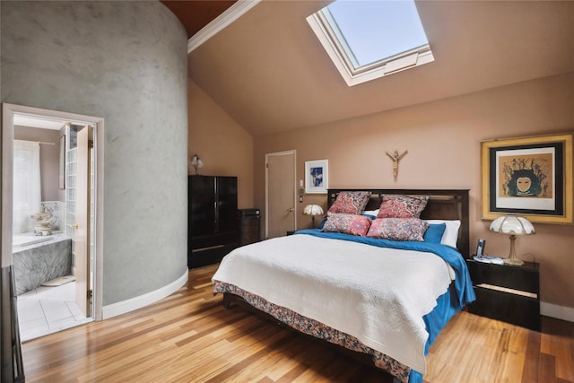 bedroom with lofted ceiling with skylight, ensuite bathroom, wood finished floors, and baseboards