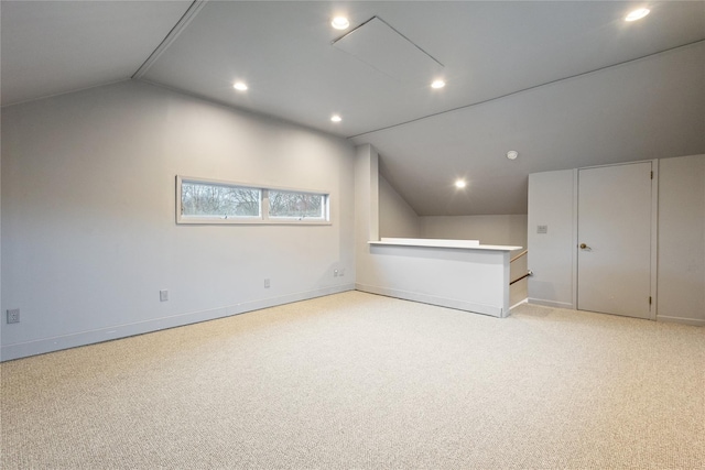 additional living space featuring baseboards, vaulted ceiling, and light carpet