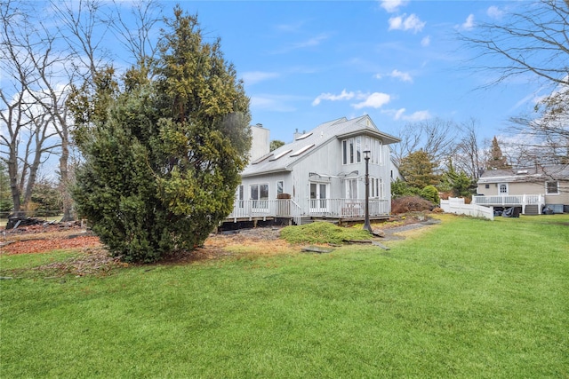 rear view of property featuring a deck and a yard