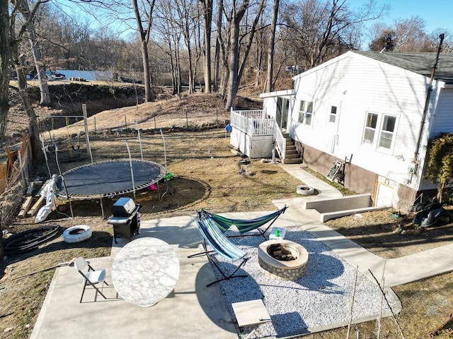 exterior space featuring a trampoline, fence, stairway, an outdoor fire pit, and a patio