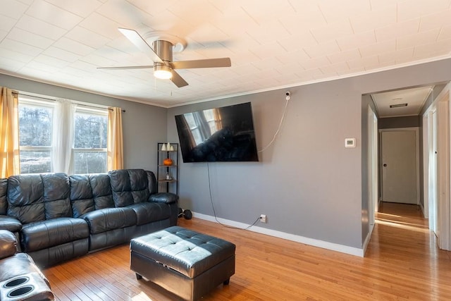 living room featuring ceiling fan, light wood-type flooring, baseboards, and ornamental molding