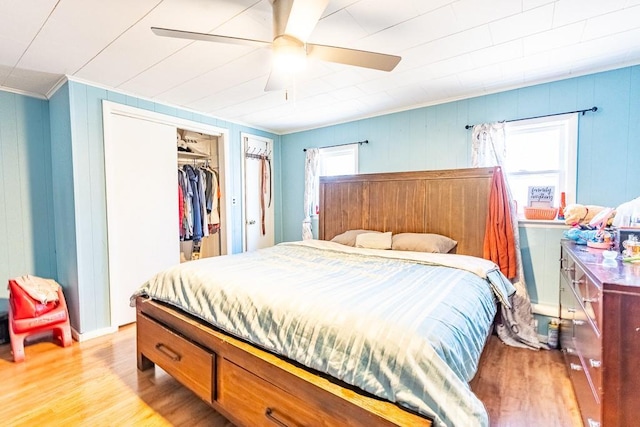 bedroom with a closet, light wood-style flooring, a ceiling fan, and crown molding