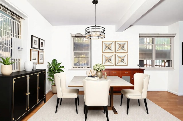 dining area featuring beamed ceiling, baseboards, a notable chandelier, and wood finished floors