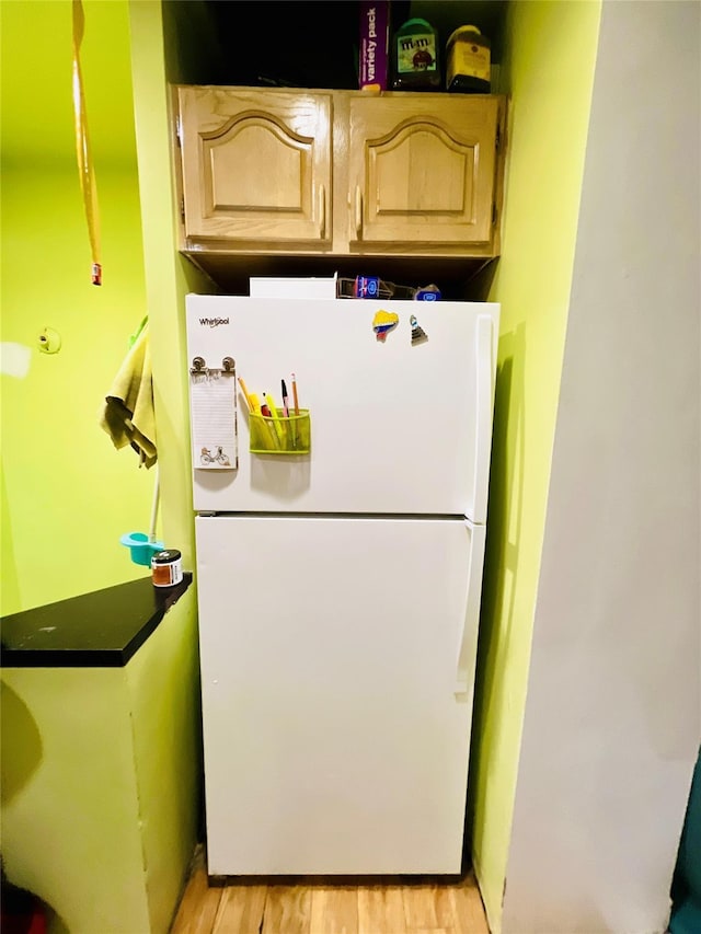 kitchen with light wood-type flooring, light brown cabinets, and freestanding refrigerator