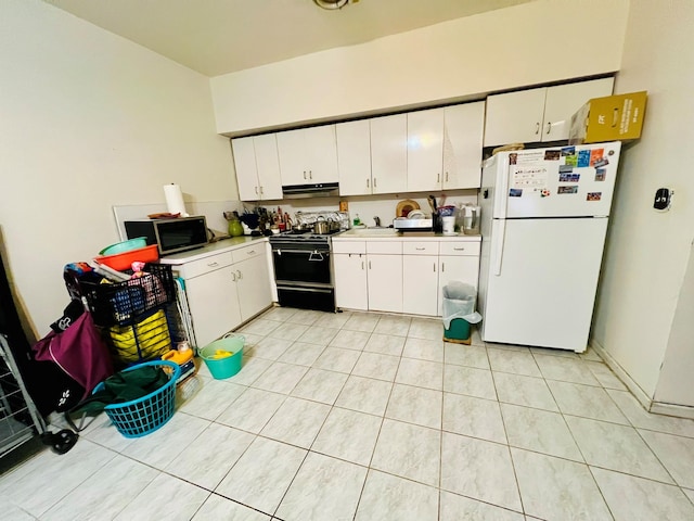 kitchen featuring freestanding refrigerator, light countertops, black gas range, white cabinets, and under cabinet range hood