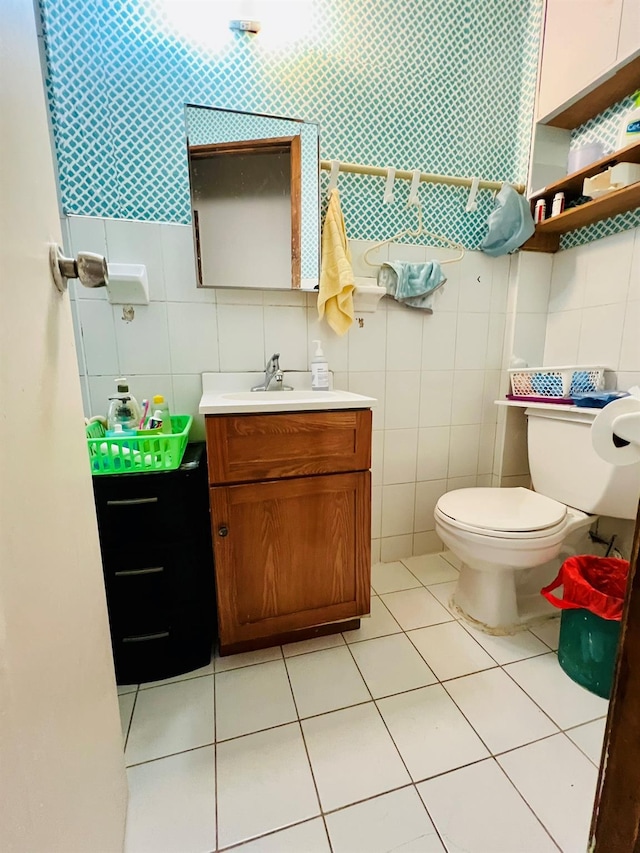 half bath with vanity, tile patterned floors, toilet, and tile walls