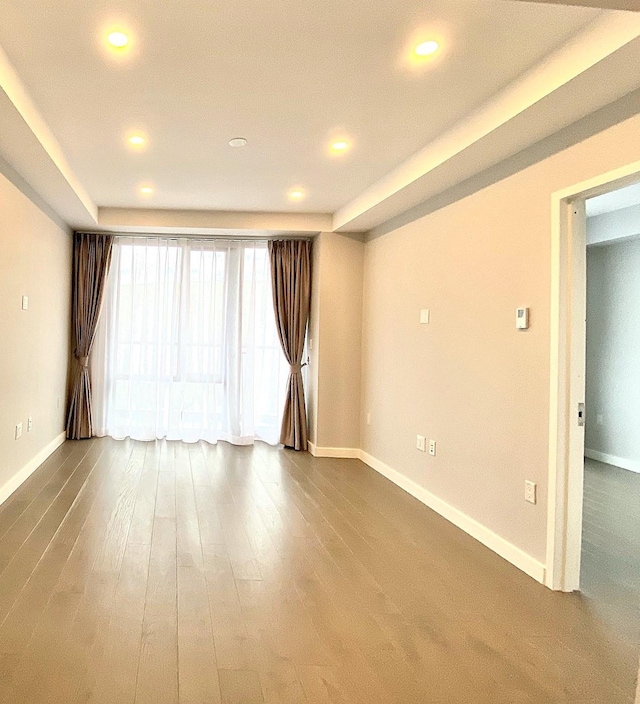 spare room featuring recessed lighting, baseboards, and wood finished floors