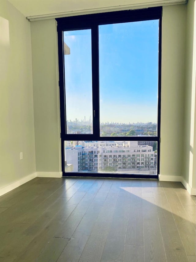 unfurnished room featuring baseboards, a view of city, and wood finished floors