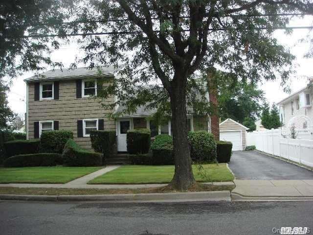 view of front facade with an outdoor structure, fence, a front lawn, and a detached garage