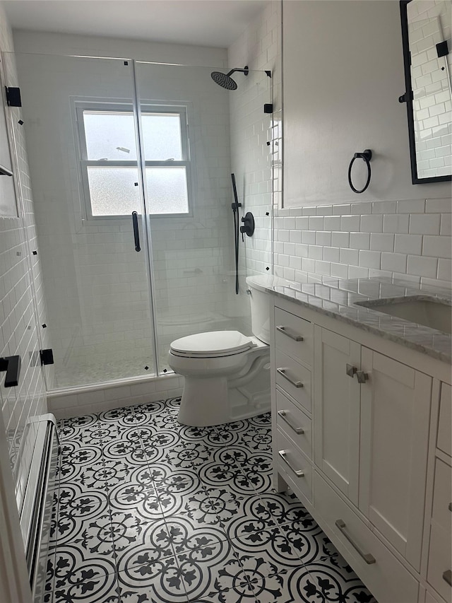 full bath with vanity, a shower stall, tile patterned floors, toilet, and tile walls