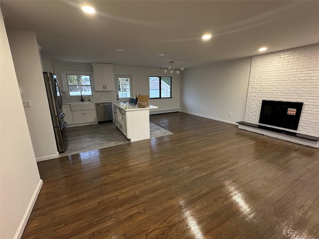 unfurnished living room featuring plenty of natural light, a fireplace, dark wood-type flooring, and a sink