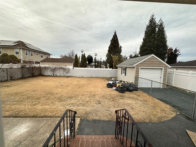 view of yard featuring a fenced backyard, driveway, an outdoor structure, and a garage