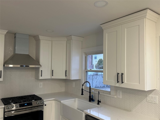 kitchen with a sink, white cabinetry, gas range, wall chimney exhaust hood, and tasteful backsplash