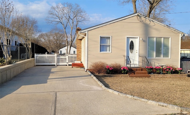 bungalow-style home with a gate, driveway, a chimney, and fence