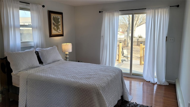 bedroom with a baseboard heating unit, multiple windows, and access to outside