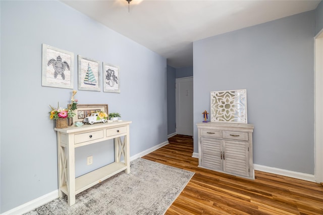 corridor featuring baseboards and wood finished floors