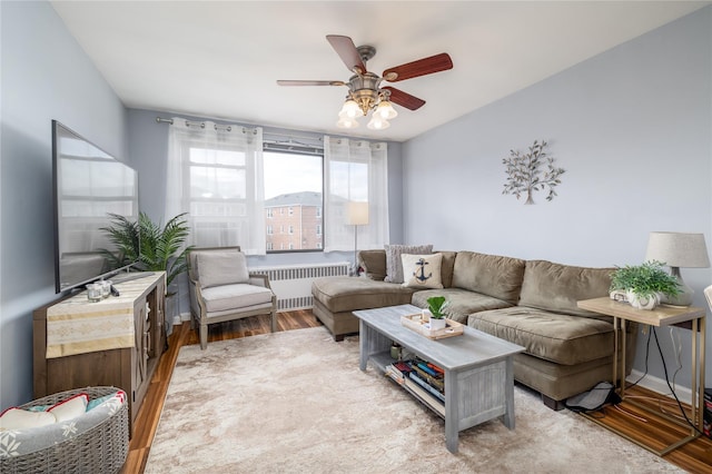 living room with baseboards, a ceiling fan, wood finished floors, and radiator heating unit