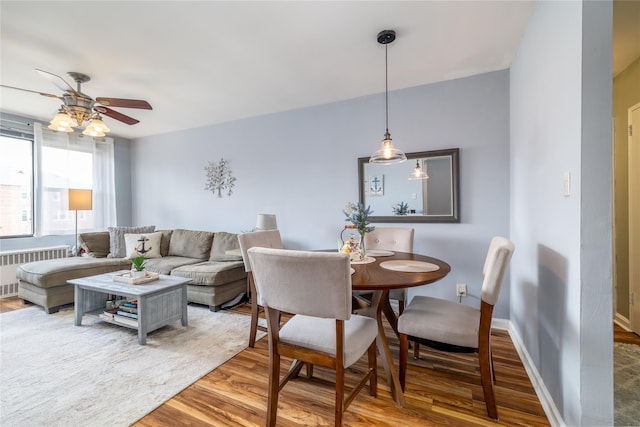 dining space with radiator, wood finished floors, baseboards, and ceiling fan