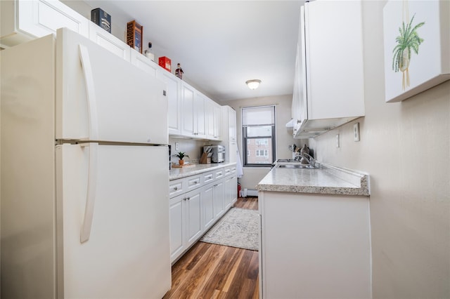 kitchen featuring light countertops, white cabinets, wood finished floors, and freestanding refrigerator