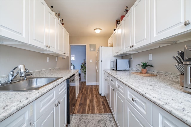 kitchen with stainless steel microwave, dishwasher, white cabinetry, and a sink