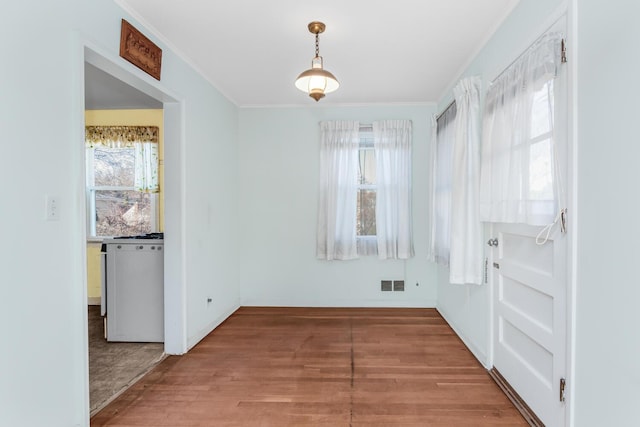 unfurnished dining area with visible vents, crown molding, and wood finished floors