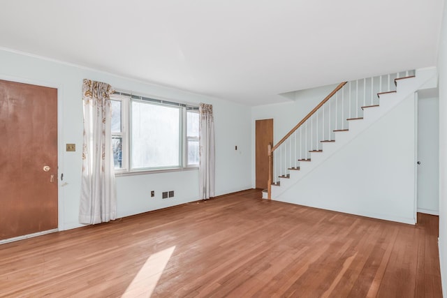 unfurnished living room featuring light wood finished floors, visible vents, and stairs