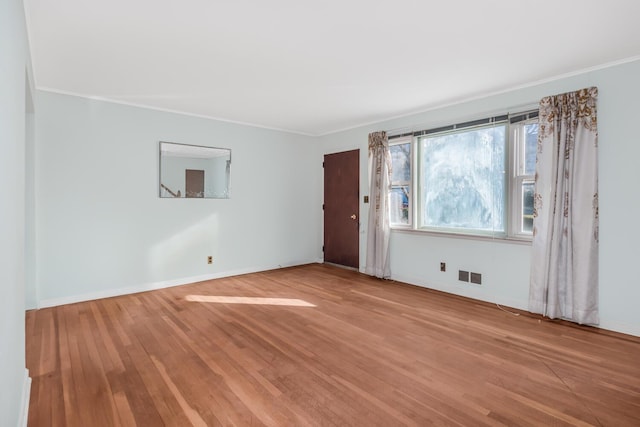 unfurnished room featuring visible vents, baseboards, light wood-style floors, and crown molding