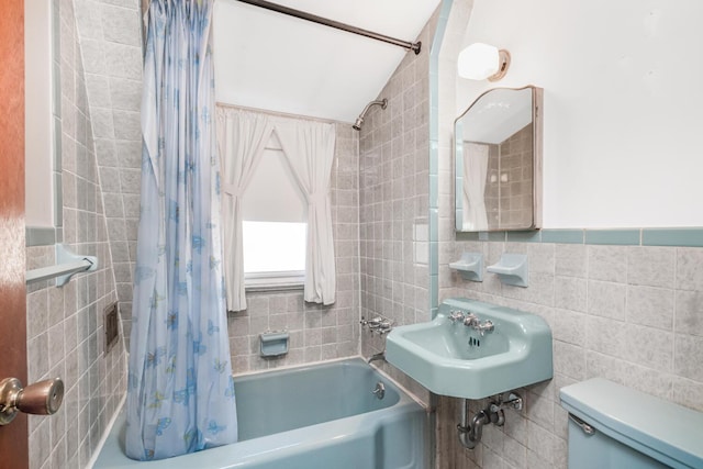 full bathroom featuring shower / bath combination with curtain, tile walls, toilet, and a sink