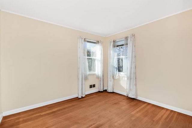 unfurnished room featuring light wood-type flooring, baseboards, visible vents, and ornamental molding