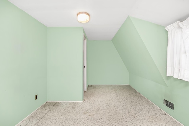 additional living space featuring visible vents, lofted ceiling, and baseboards