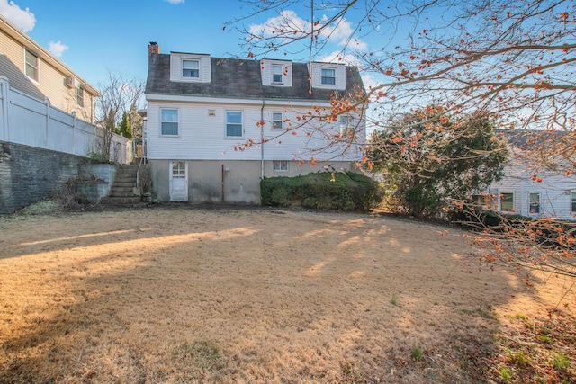 back of house featuring stairway, a lawn, and a chimney