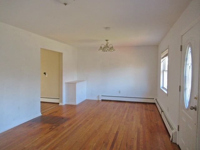 spare room with a notable chandelier, wood finished floors, and a baseboard radiator