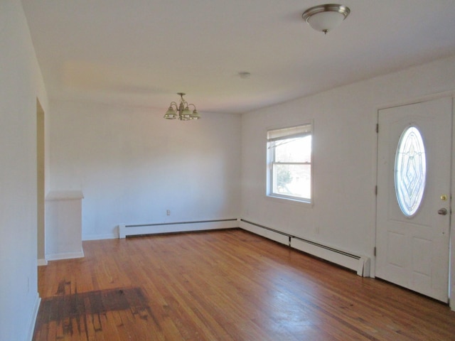 foyer entrance featuring a chandelier, wood finished floors, baseboard heating, and a baseboard radiator